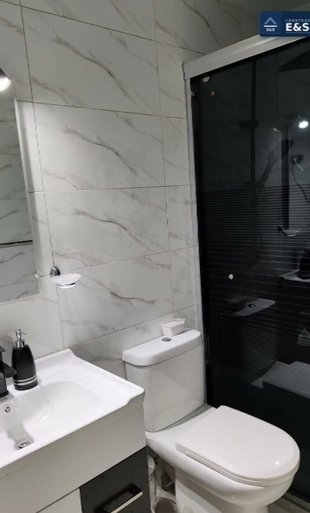 Baño remodelado con cerámica símil mármol y grifería negra mate
