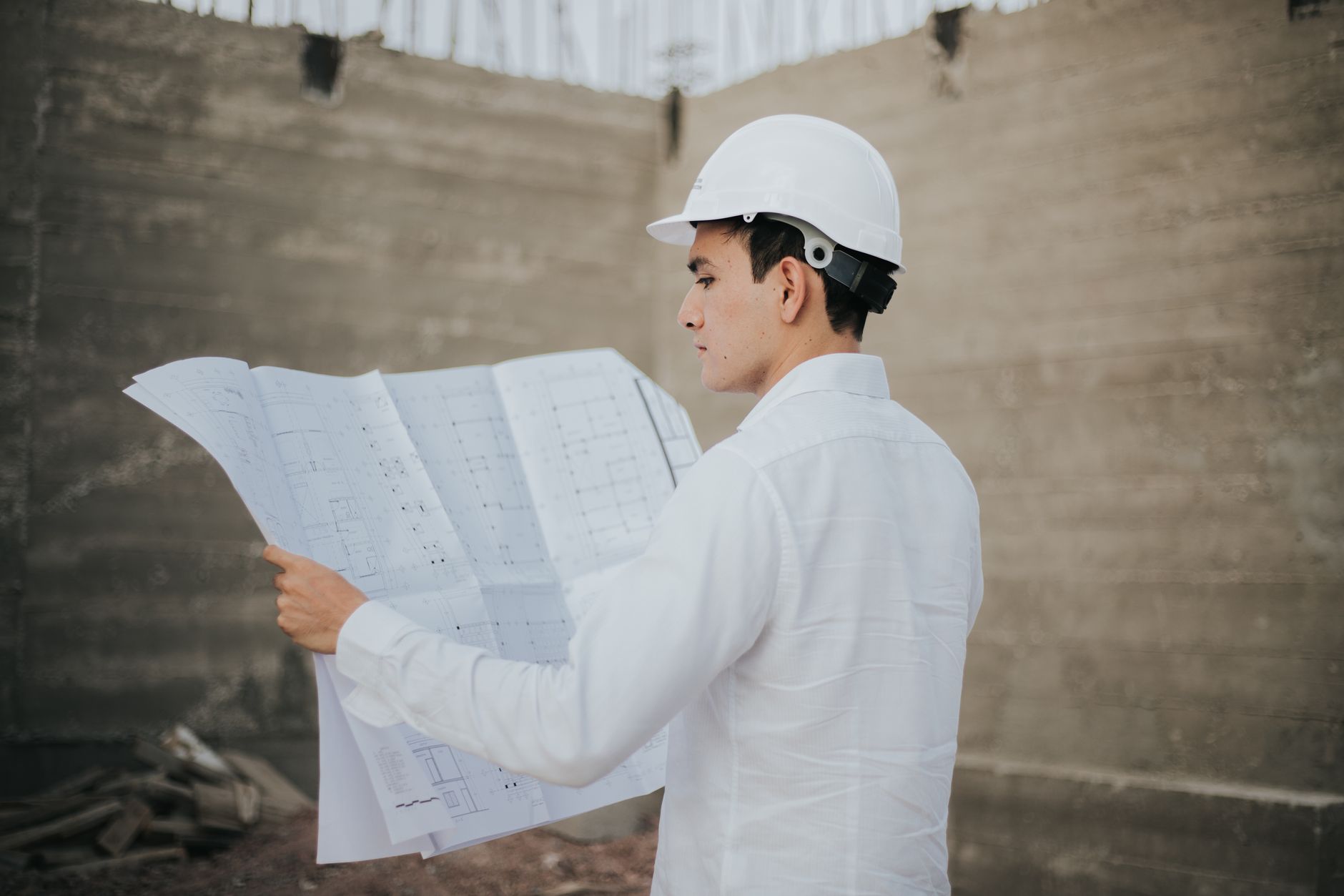 Profesional con casco revisando planos de construcción